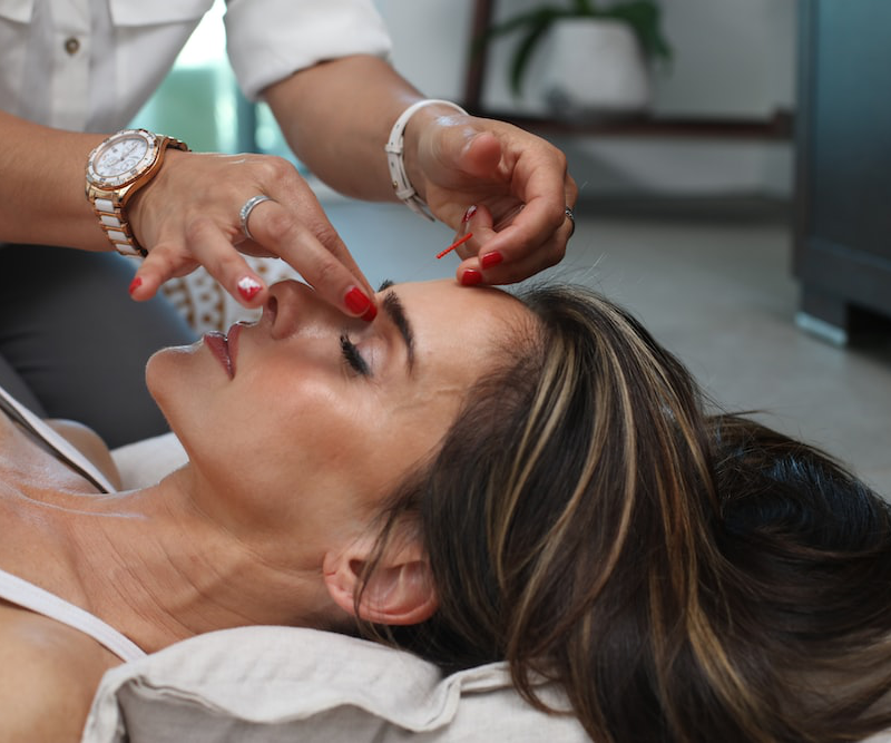 a woman getting facial acupuncture treatment.